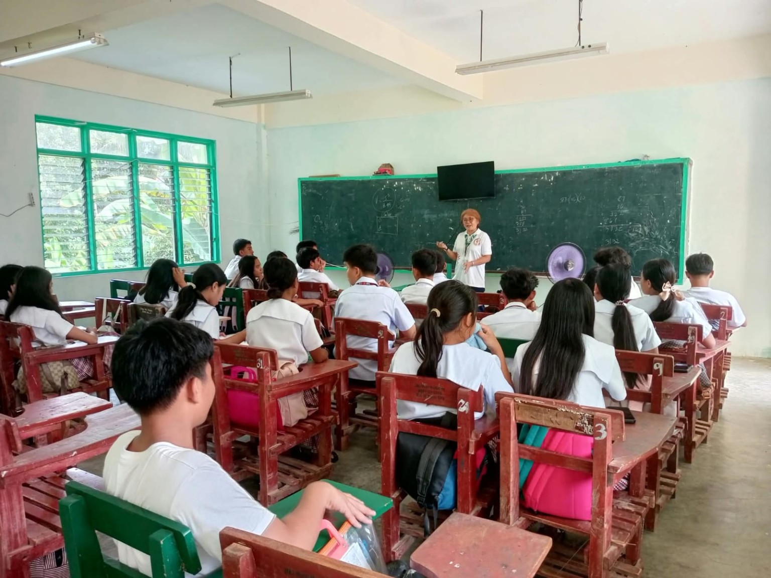 A volunteer speaking with students in a classroom